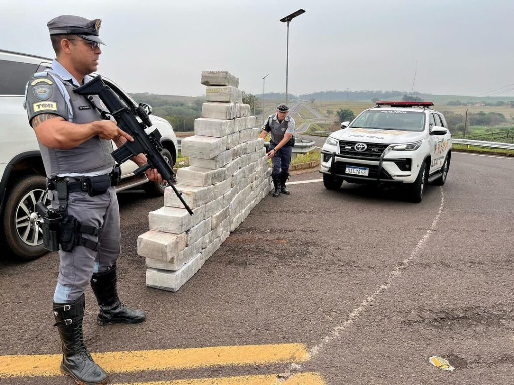 Policial rodoviário ao lado da pilha de fardos de maconha - Colab./Polícia Rodoviária